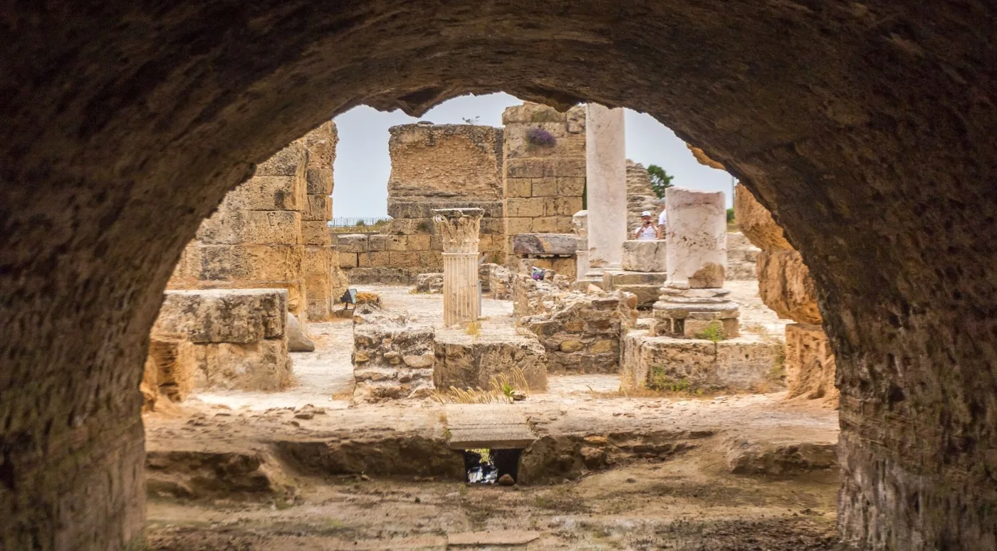 Carthage ruins framed by a curved stone arch in the vaults of the Antonine Baths