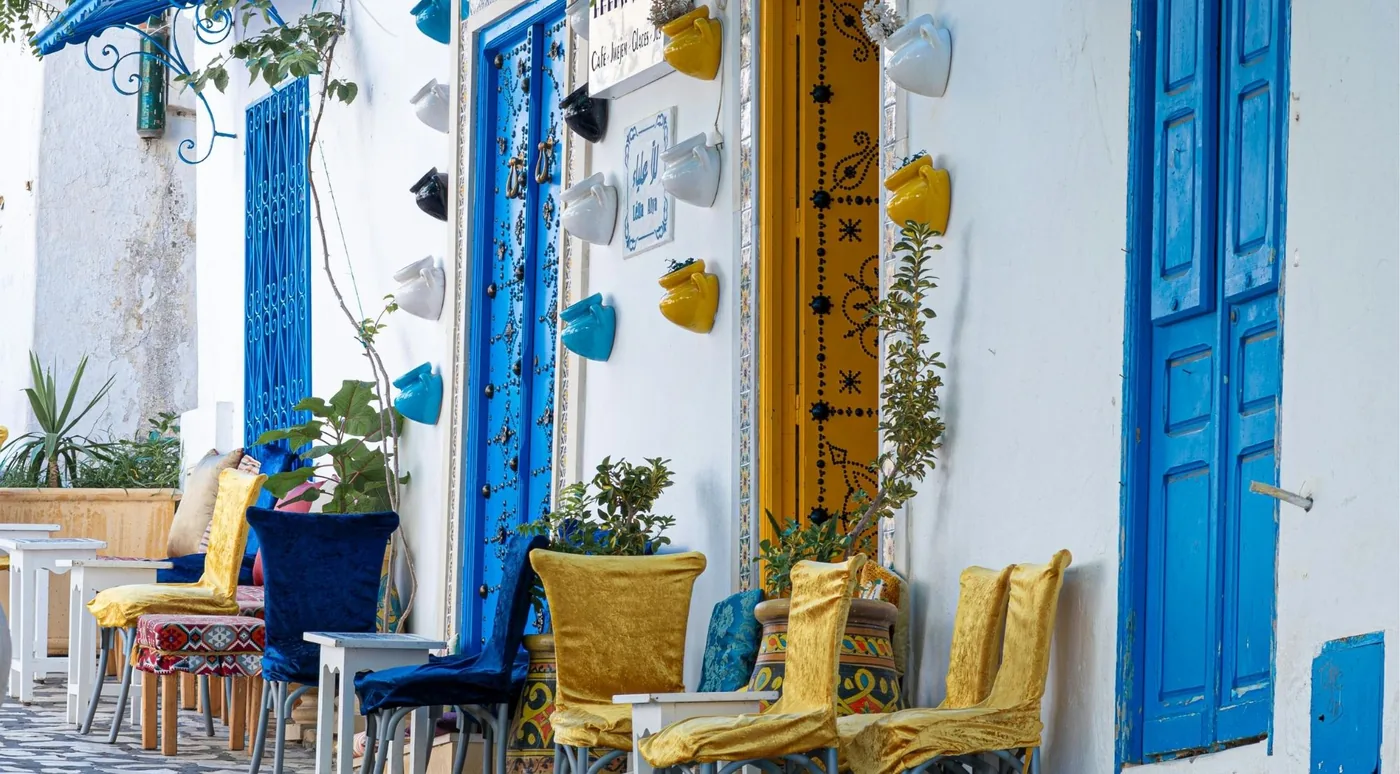 A blue café terrace in Sidi Bou Said with yellow cushions and hanging ceramics