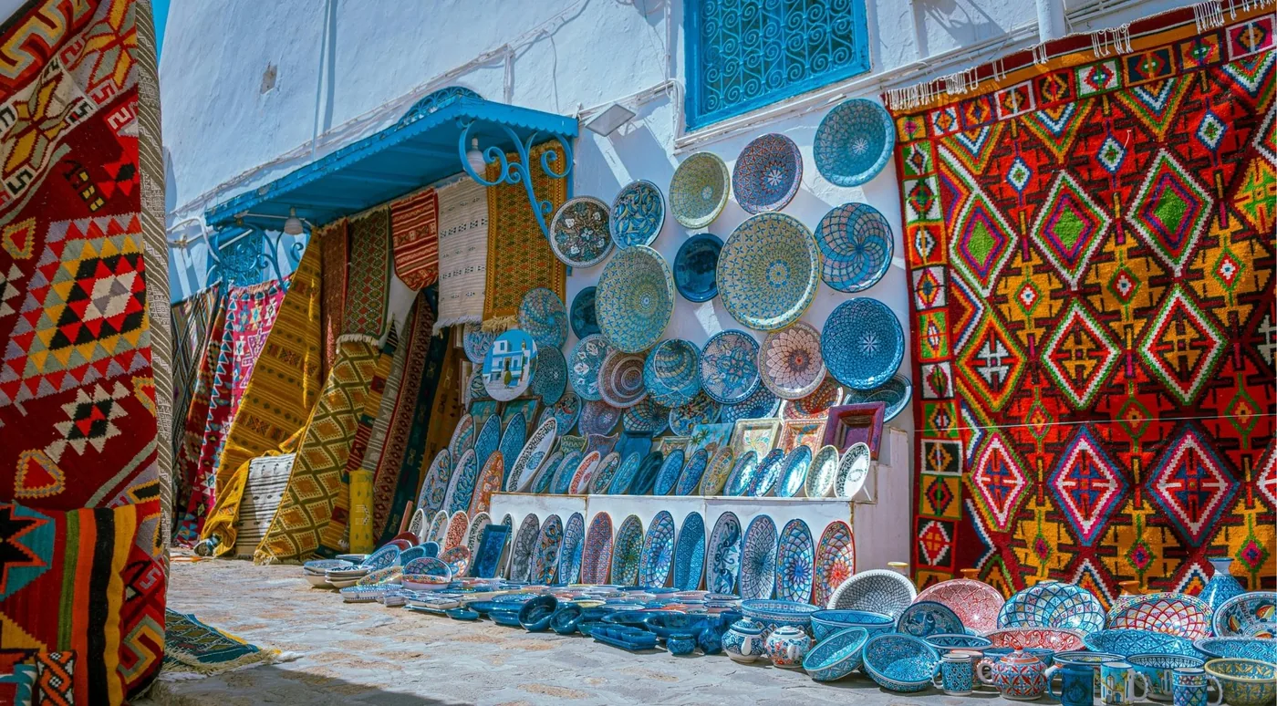 A wall of Tunisian ceramics and woven carpets outside a Sidi Bou Said shop