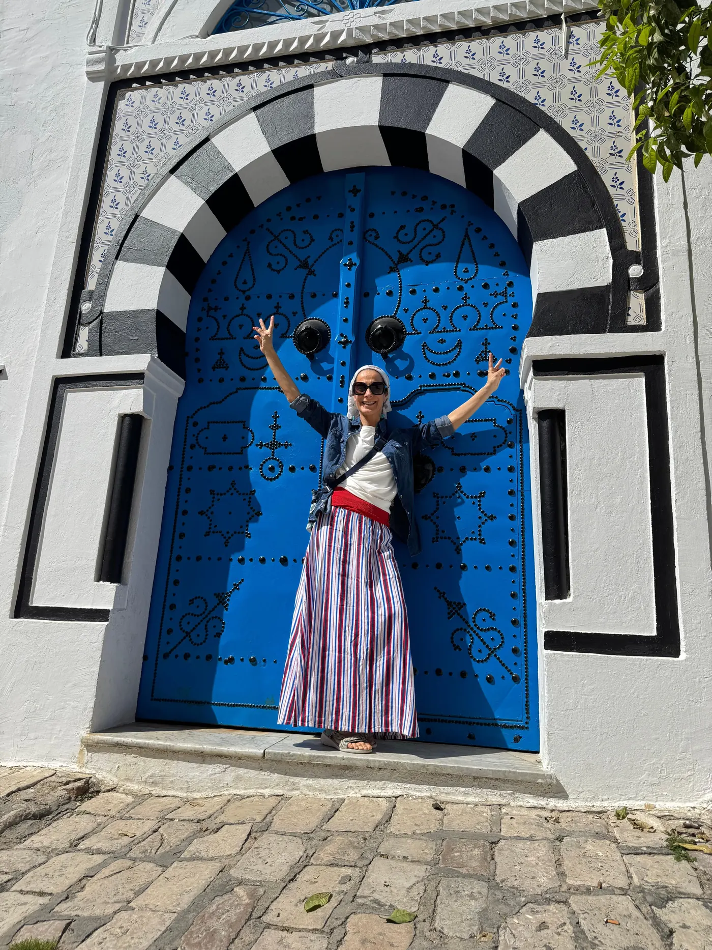 A studded blue Sidi Bou Said door framed in a white horseshoe arch