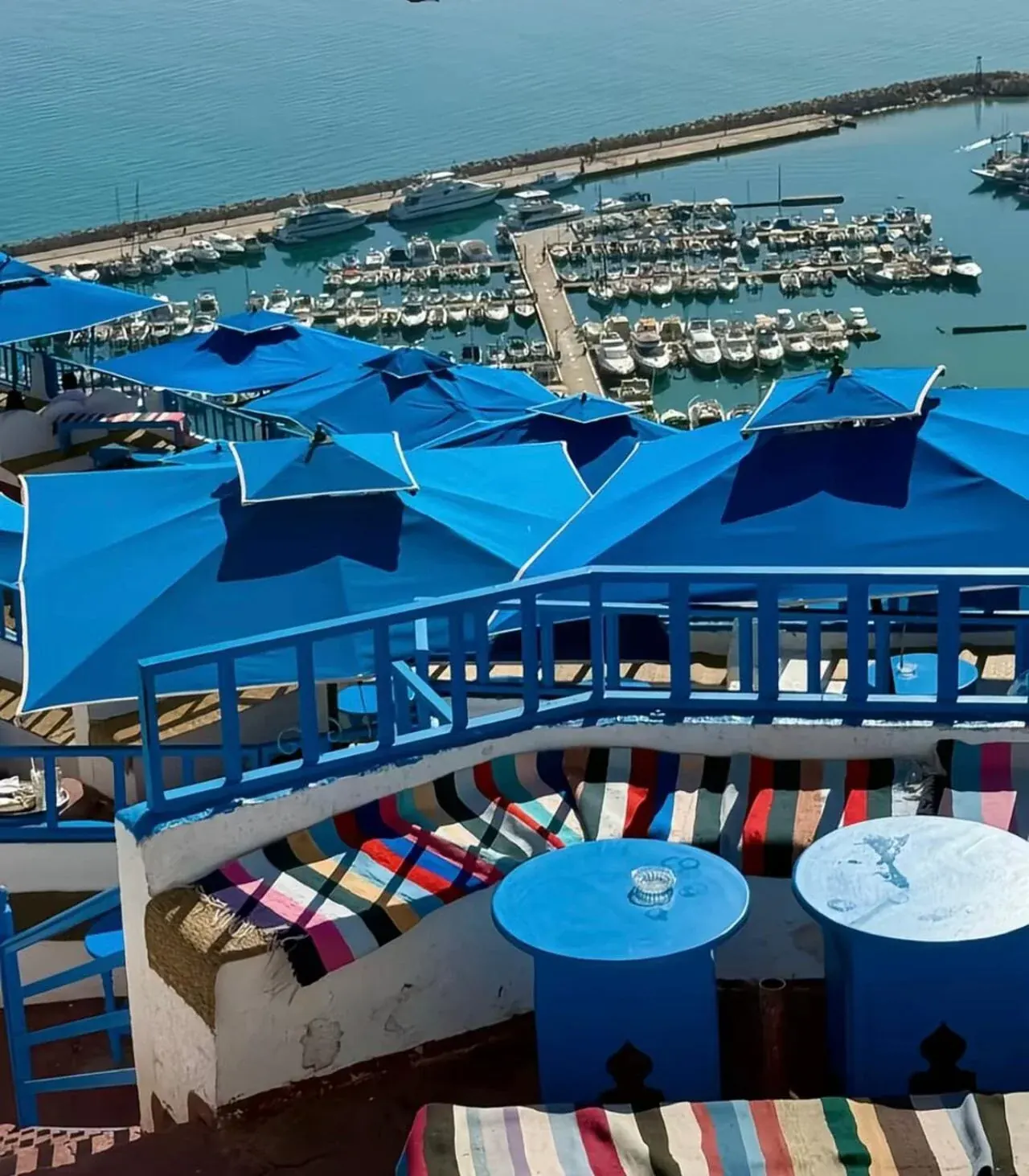 Blue parasols on a clifftop café terrace above the Sidi Bou Said marina