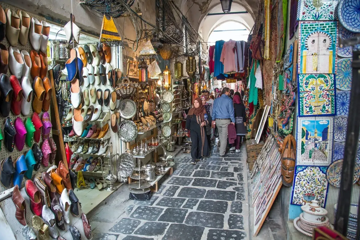Leather slippers and textiles filling a souk alley in the Tunis medina