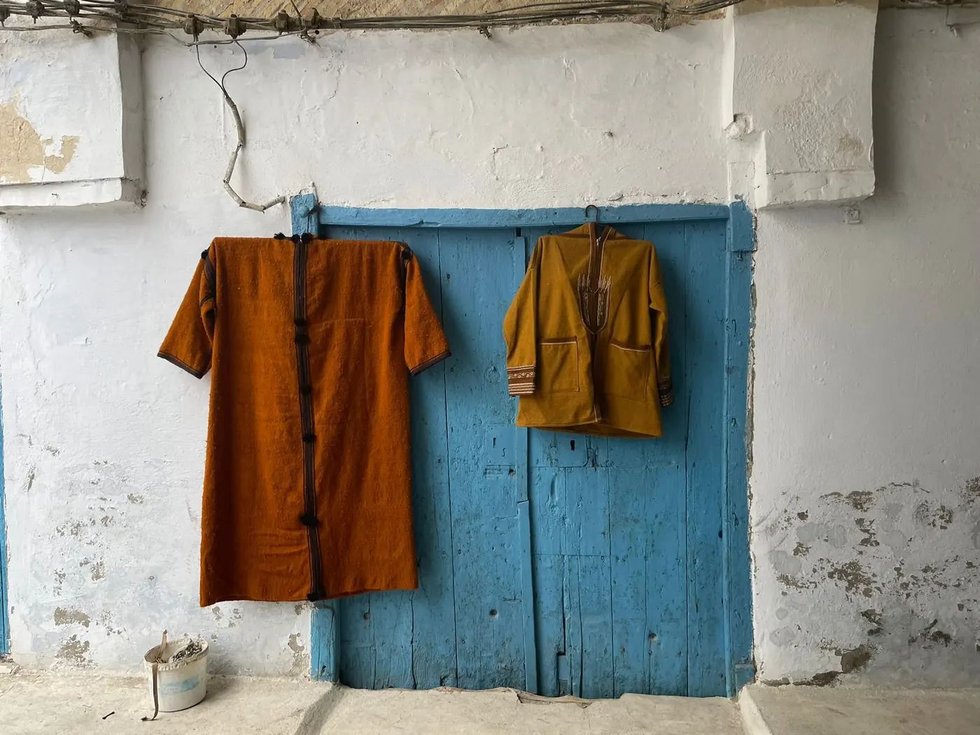 Traditional robes hanging on a weathered blue door in Sidi Bou Said