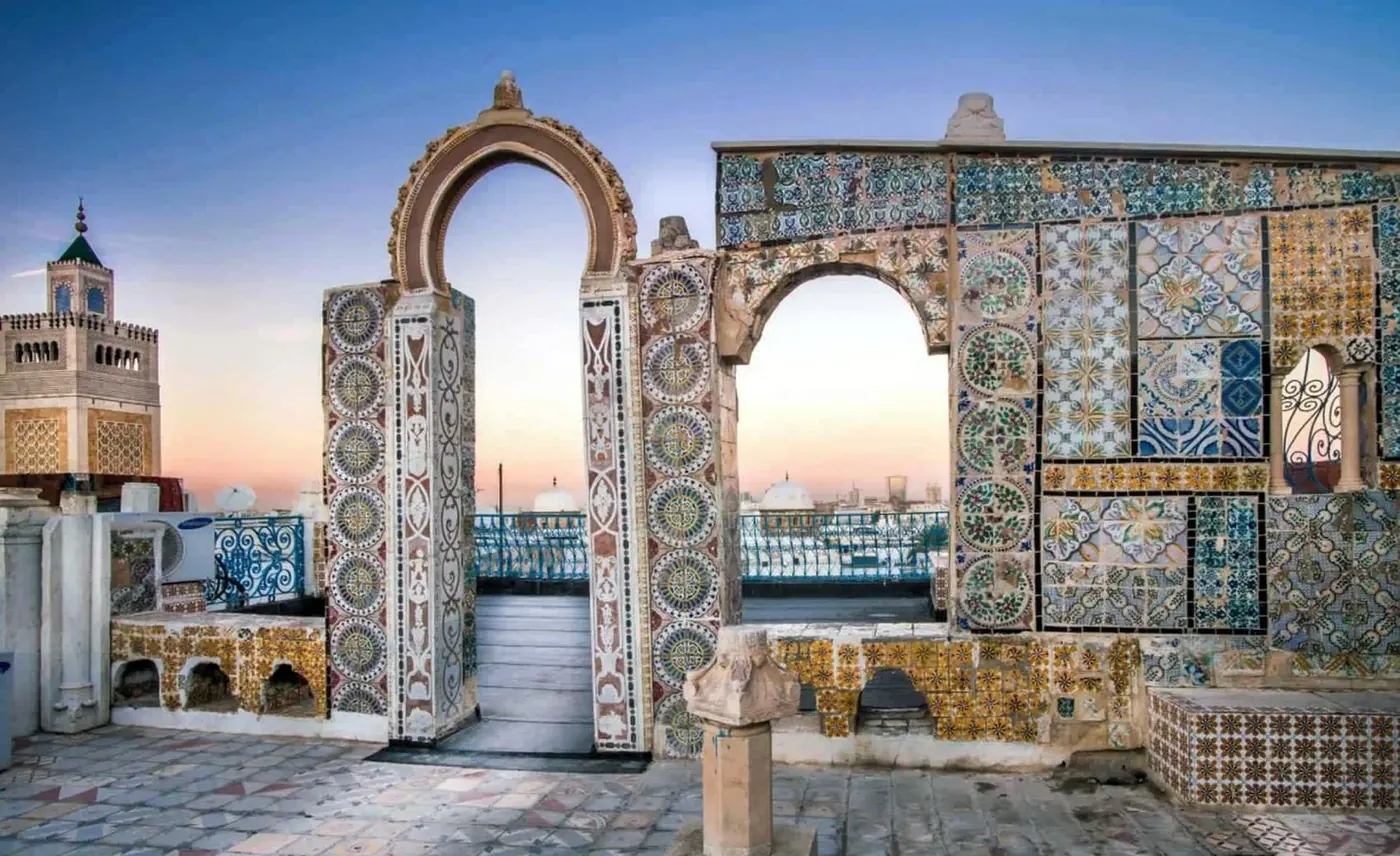 Tiled horseshoe arches framing a rooftop view over the Tunis medina