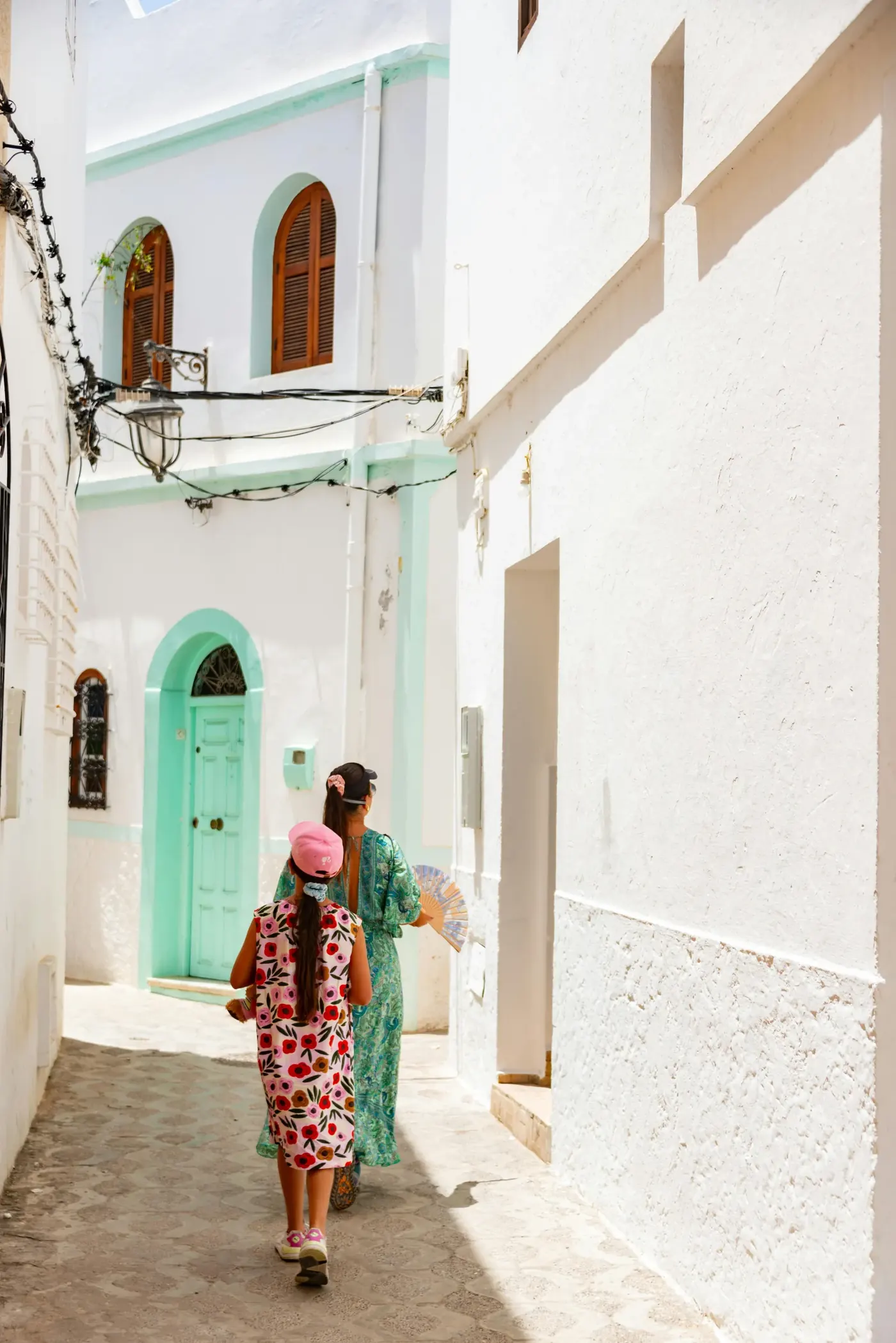 A white lane and a green studded door in the medina